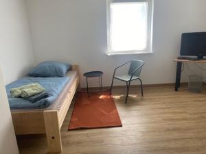 a bedroom with a bed and two chairs and a television at WORK & Rest Monteurzimmer in Batzhausen