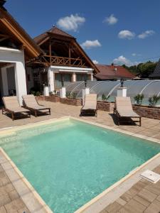 a swimming pool with chairs and a house at Mariska in Balatonkeresztúr