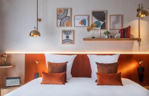 a bedroom with a bed with orange and white pillows at Hôtel Burdigala by Inwood Hotels in Bordeaux