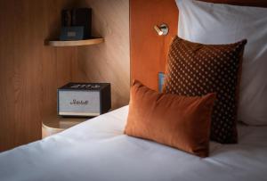 a bed with a pillow and a alarm clock at Hôtel Burdigala by Inwood Hotels in Bordeaux