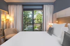 a hotel room with a large bed and a balcony at Hôtel Arcanse by Inwood Hotels in Arcachon