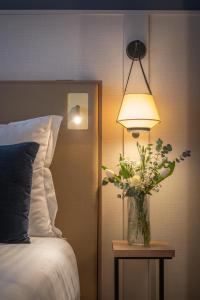 a vase of flowers on a table next to a bed at Hôtel Arcanse by Inwood Hotels in Arcachon