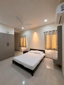 a bedroom with a white bed and two windows at Veechi Retreat in Secunderabad