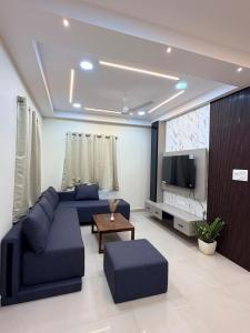 a living room with a blue couch and a tv at Veechi Retreat in Secunderabad