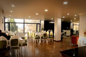 a dining room with white tables and chairs and windows at Sapphire Hotel & Convention Centre in Baddi
