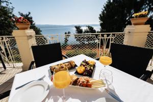 a table with a plate of food and two glasses of orange juice at Hotel Lovran in Lovran