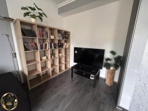 a living room with a television and book shelves at Ural Home in Székesfehérvár