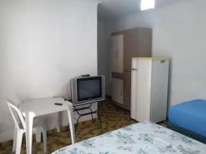 a room with a table and a tv and a bed at Suites no centro, Salto-SP in Salto