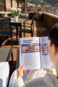 a woman reading a book in a restaurant at Residence San Marco Suites&Apartments Alassio in Alassio