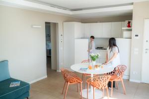two people in a kitchen with a table and chairs at Residence San Marco Suites&Apartments Alassio in Alassio