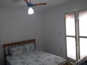 a bedroom with a bed with a ceiling fan and a window at Suites no centro, Salto-SP in Salto