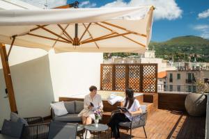two women sitting on a patio with an umbrella at Residence San Marco Suites&Apartments Alassio in Alassio +39 photos