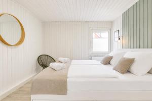 a white bedroom with a large white bed and a mirror at Schiller in Wandlitz
