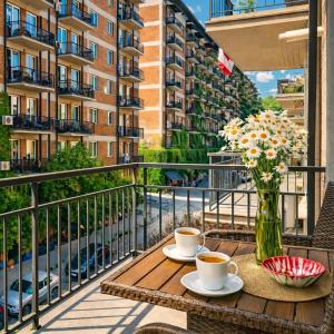 a table with two cups of coffee and flowers on a balcony at Home Inn Apartments Your house Jikia-Central Tbilisi in Tbilisi City