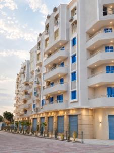 a large white apartment building with blue windows at Bianco Matrouh Hotel in Marsa Matruh
