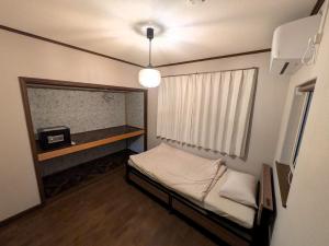 a small room with a bed and a window at Frasis in Furano