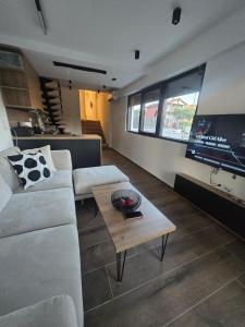 a living room with a white couch and a table at Grey Pearl Apartments in Nea Kallikrateia