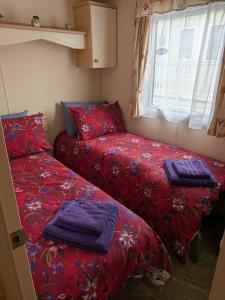 two beds in a small room with red sheets at Ocean View in Aberaeron