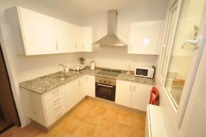 a kitchen with white cabinets and a sink and a microwave at casa Bayer in Benicàssim