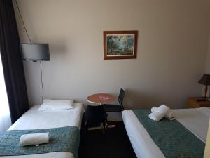 a hotel room with two beds and a table at Gateshead Tavern & Motel in Charlestown