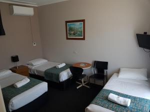 a hotel room with three beds and a table and chairs at Gateshead Tavern & Motel in Charlestown