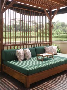 a green couch with pillows and a table on a porch at Dijero at Umah Bali in Ubud