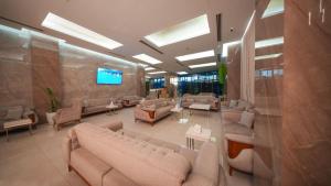 a large lobby with couches and tables and a television at BAZ Hotel University District in Baghdād