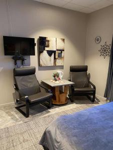 a bedroom with two chairs and a table and a tv at Svenningdal Camping in Svenningdal