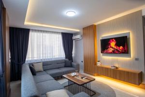 a living room with a couch and a fire painting on the wall at Gala Mtm Konaklama in Çiftlikköy