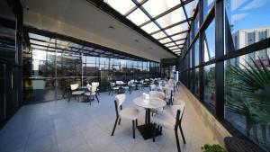 a restaurant with white chairs and tables and windows at BAZ Hotel University District in Baghdād