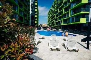 Eine Gruppe weißer Stühle steht um einen Swimmingpool herum in der Unterkunft Bavaro 28 by Alezzi Resort in Mamaia Nord – Năvodari
