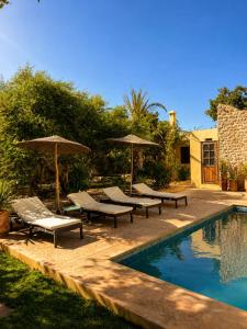 a swimming pool with chairs and umbrellas next to a swimming pool at Maison Zina in Al Ghar