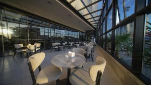 a restaurant with tables and chairs and windows at BAZ Hotel University District in Baghdād