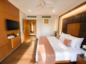 a bedroom with a large bed and a flat screen tv at Golden Palace Puri - Private Flagship Beach - Swimming Pool - Sea View Rooms - Restaurant - Luxurious Stay in Puri