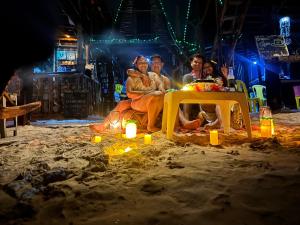 a group of people sitting on the beach at night at Tipiland baru la casa del mono in Playa Blanca