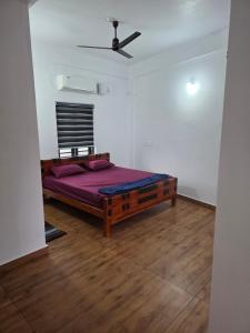 a bedroom with a bed with purple sheets and a ceiling at Ruby Residency in Perintalmanna +6 photos