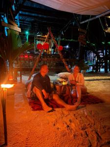 a man and a woman sitting at a table on the beach at Tipiland baru la casa del mono in Playa Blanca