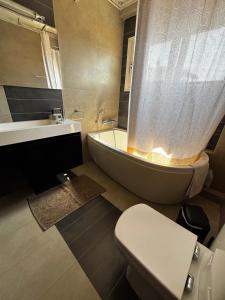 a bathroom with a tub and a toilet and a sink at Luminous Home in Vari +24 photos