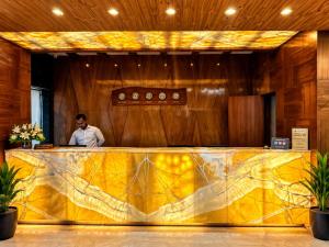 a man standing behind a yellow counter in a room at Golden Palace Puri - Private Flagship Beach - Swimming Pool - Sea View Rooms - Restaurant - Luxurious Stay in Puri