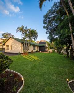 a yard with a house and palm trees at Moxley Manor in Durban