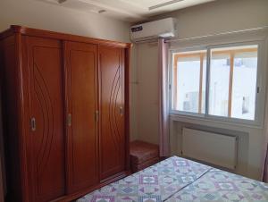 a bedroom with a wooden cabinet and a window at Paradise Days in Sfax