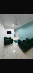 a living room with two green couches and a tv at Brufut Residencies Apartment 5 in Brufut