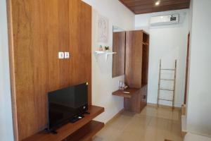 a living room with a flat screen tv on a wooden wall at Lantis Corp Inn in Sengkol