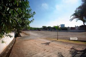 an empty parking lot with a fence and a tree at Hotel Caminho do Rosário in Aparecida