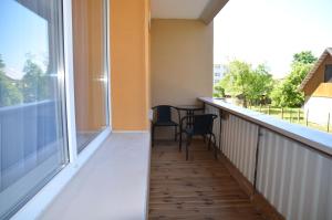a balcony with a table and chairs and a large window at Merķeļa apartamenti in Valka