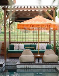 a couch under an umbrella next to a pool at Dijero at Umah Bali in Ubud +27 photos