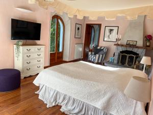 a bedroom with a white bed and a fireplace at Villa Zanotti in Cannero Riviera