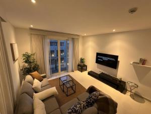 a living room with a couch and a flat screen tv at Thewalk2 Pool View ~ 5 mins from Airport in Seeb