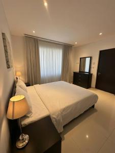a bedroom with a bed with a lamp and a window at Thewalk2 Pool View ~ 5 mins from Airport in Seeb