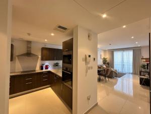 a kitchen with brown cabinets and a dining room at Thewalk2 Pool View ~ 5 mins from Airport in Seeb +4 photos
